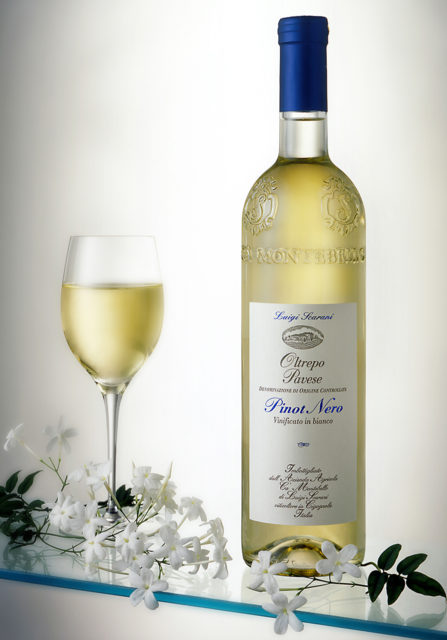 Foto still life del vino Pinot nero vinificato bianco con bicchiere e fiori di gelsomino su fondo neutro